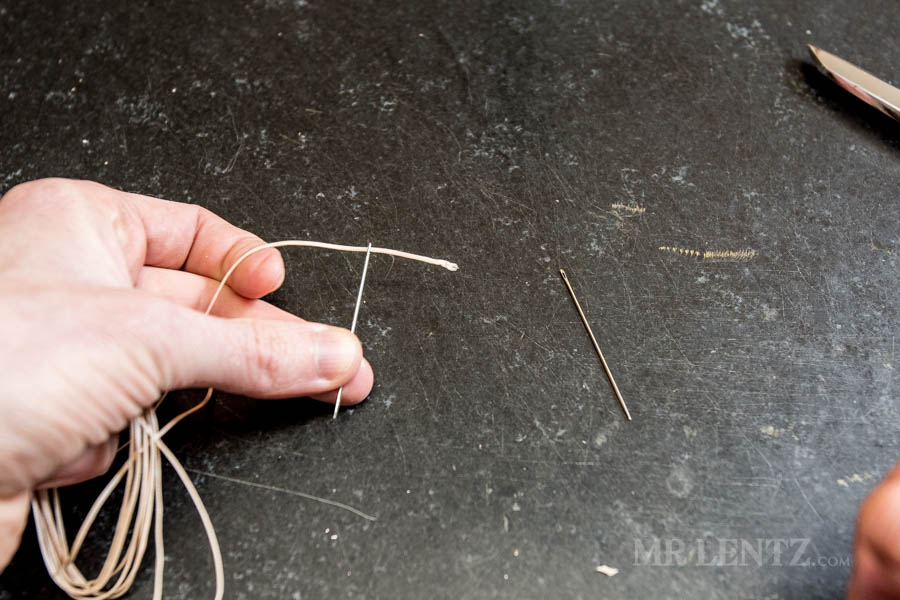 feeding thread through eye of the needle before sewing through leather