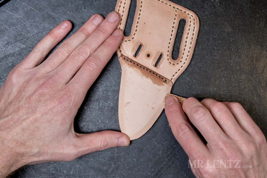 sanding the welt on a leather knife sheath